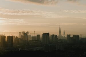 Silhouette of Kuala Lumpur skyline during sunrise with misty atmosphere, showcasing skyscrapers and urban landscape.